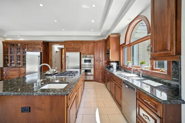 a kitchen with stainless steel appliances granite countertop a sink a stove and a wooden cabinets
