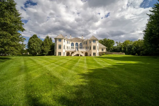 a view of a house with a big yard and large trees