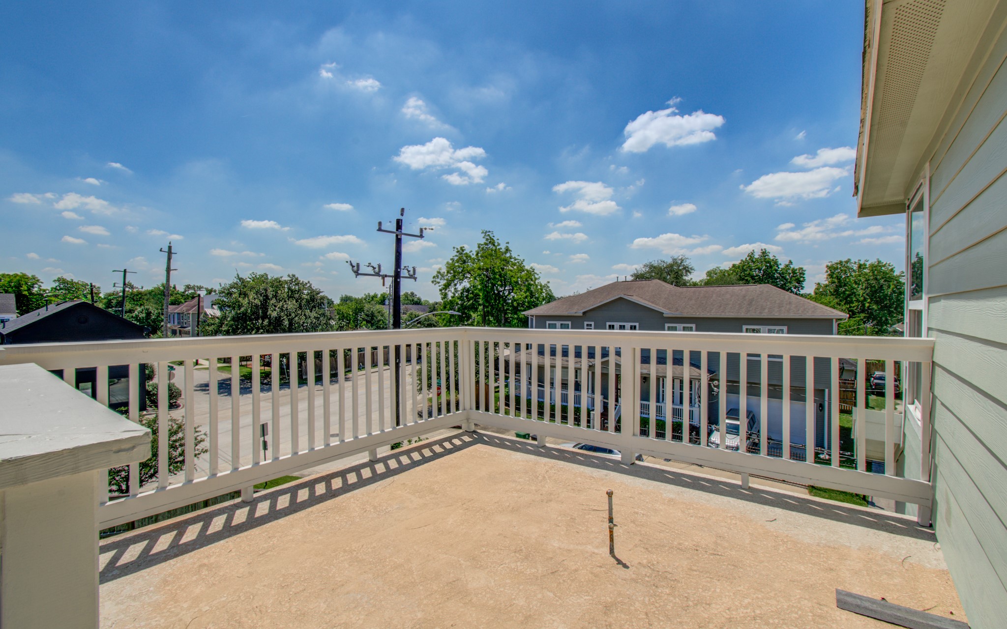 6621 North Main Street Houston, TX 77009 - Photo 22 of 41 Elevated balcony with a white railing, offering a view of a suburban neighborhood. The area is bright and open, perfect for enjoying outdoor relaxation or entertaining.