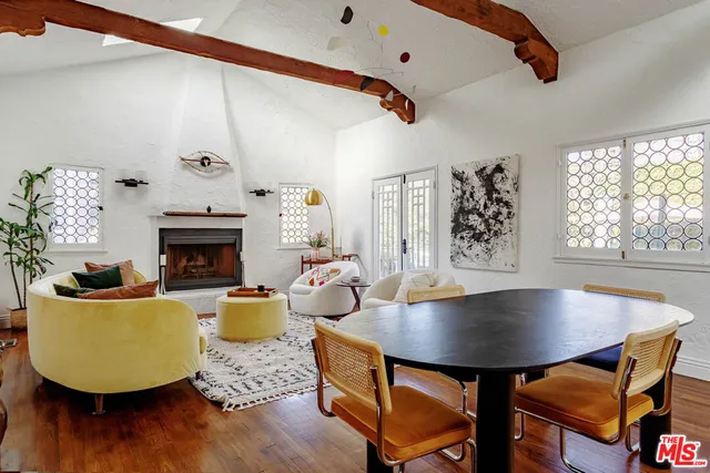 a living room with dining table a window potted plants and a fireplace