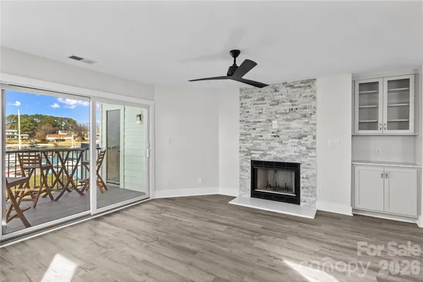 a view of an empty room with wooden floor and a fireplace