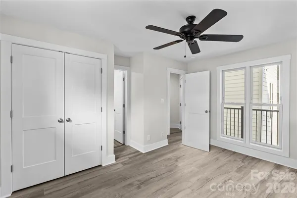 a view of an empty room with wooden floor and a ceiling fan