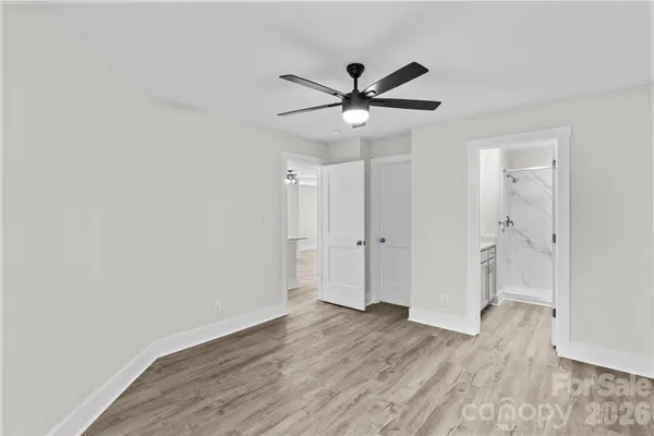 an empty room with wooden floor fan and windows