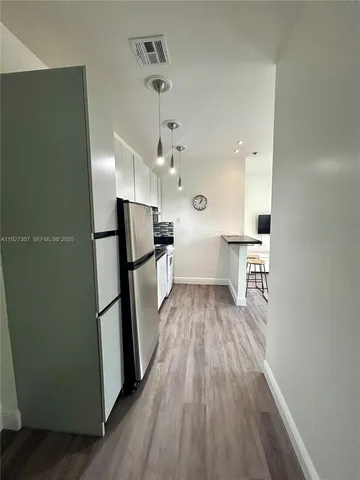 a kitchen with stainless steel appliances a refrigerator and wooden floor