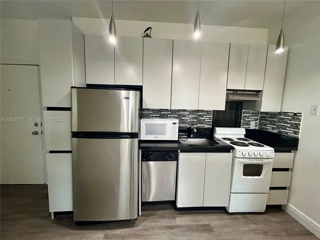 a kitchen with a refrigerator a stove and a wooden floors