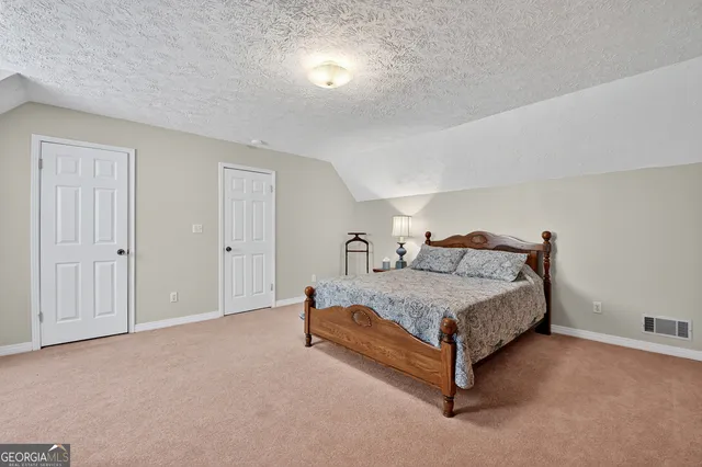 a spacious bedroom with a bed and a lamp