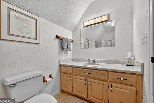 a bathroom with a granite countertop toilet sink and mirror