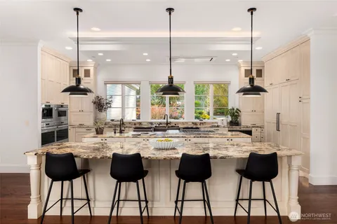a kitchen with stainless steel appliances kitchen island granite countertop a dining table chairs and white cabinets