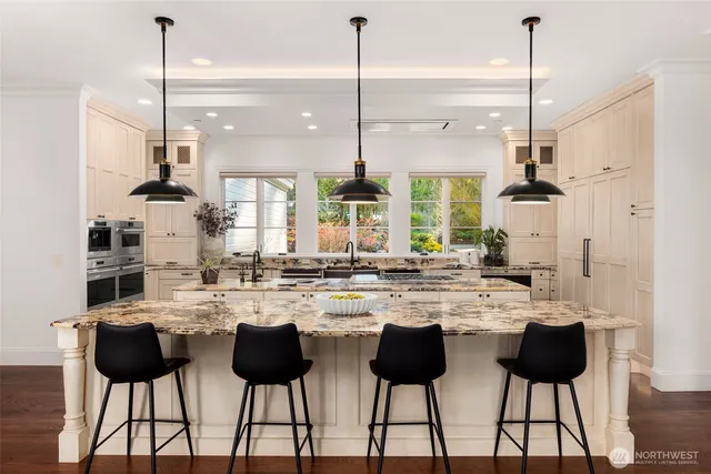 a kitchen with stainless steel appliances kitchen island granite countertop a dining table chairs and white cabinets