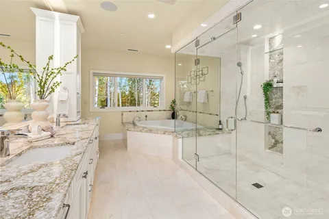 a large bathroom with a granite countertop sink a mirror a bathtub and next to a window