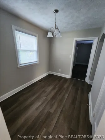an empty room with wooden floor cabinet and windows