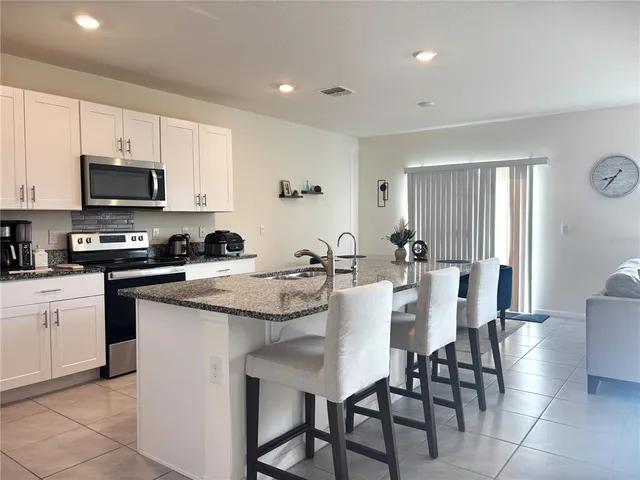 a kitchen with stainless steel appliances granite countertop a table chairs microwave and sink