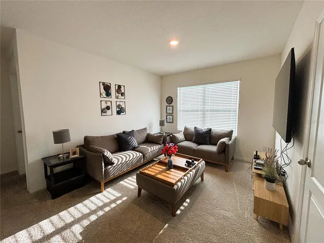 a living room with furniture a flat screen tv and a window