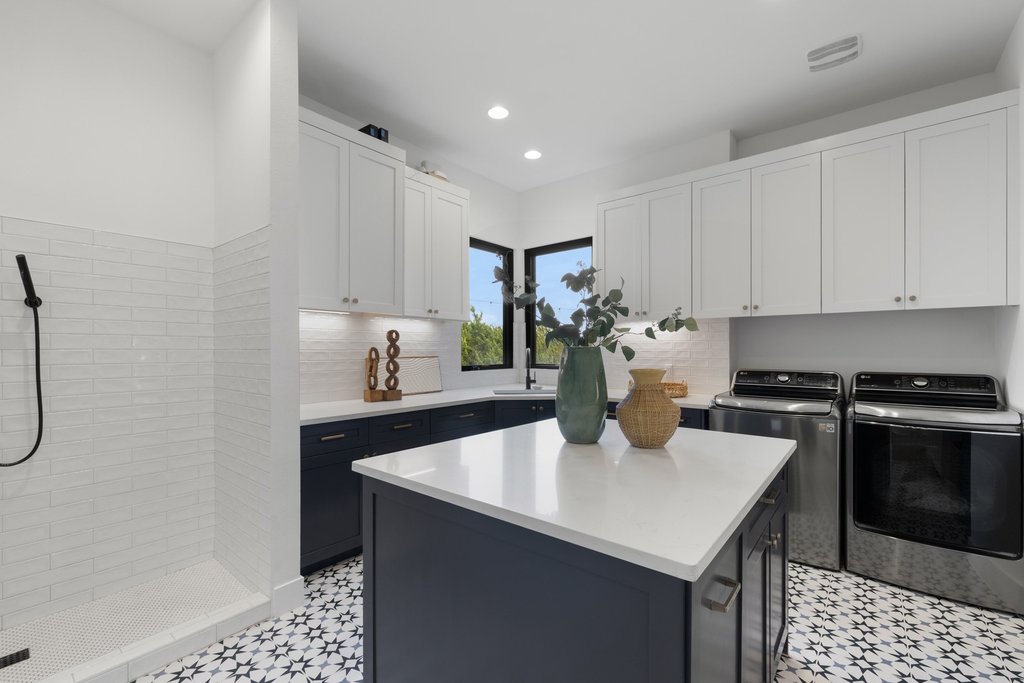 6316 Caudill Lane Austin, TX 78738 - Photo 20 of 40 Kitchen with dual tone cabinets, a kitchen island, washer and clothes dryer, stainless steel range, and tasteful backsplash