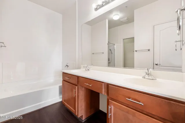 a bathroom with a sink double vanity granite tub and a mirror