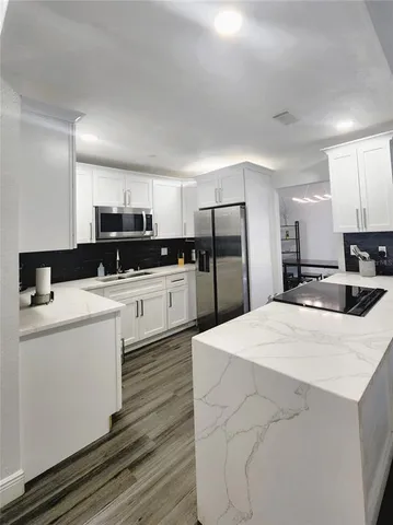 a kitchen with a sink a stove a refrigerator and white cabinets