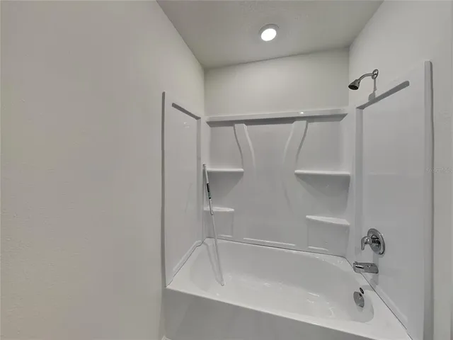 a white bath tub sitting next to a white sink and vanity