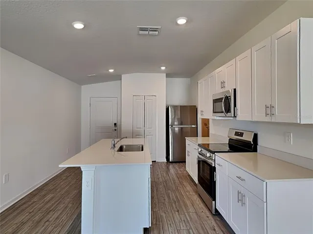 a kitchen with a sink a counter top space stainless steel appliances and cabinets