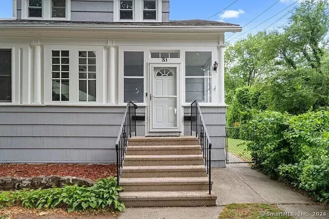 a view of a house with potted plants and a fountain