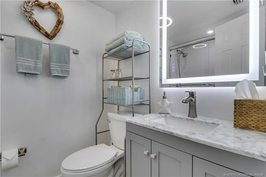 1001 Keystone Drive, Unit A Jupiter, FL 33458 - Photo 17 of 30 a bathroom with a granite countertop sink a toilet and a mirror