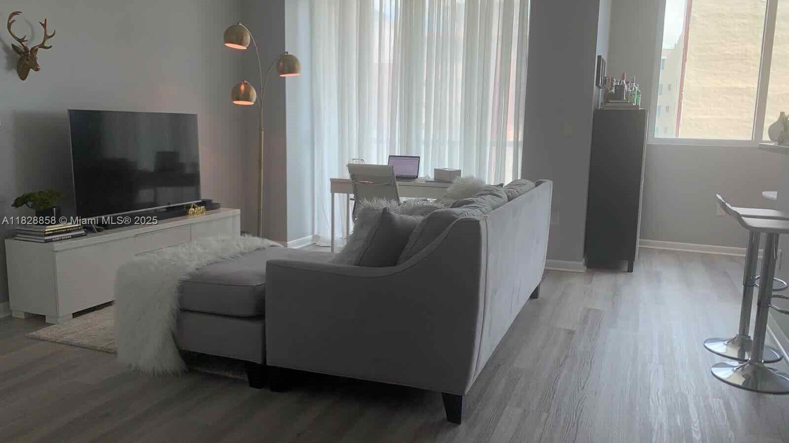 244 Biscayne Boulevard, Unit 608 Miami, FL 33132 - Photo 2 of 25 a living room with furniture and a flat screen tv