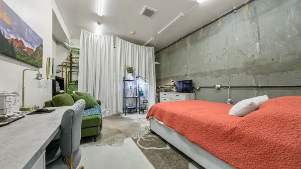 a bedroom with a refrigerator and a wooden floor