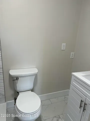 a white toilet sitting next to a white wall