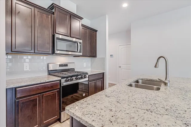 a kitchen with granite countertop stainless steel appliances and a sink