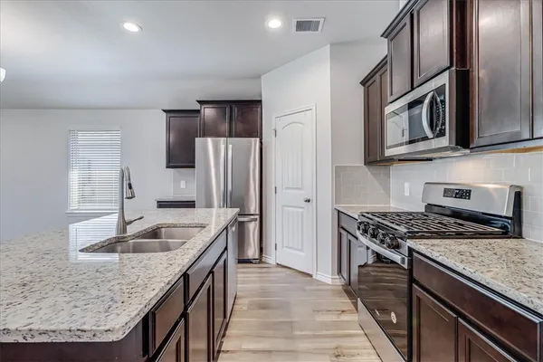 a kitchen with stainless steel appliances granite countertop a sink stove and refrigerator