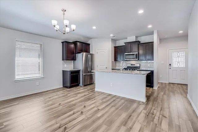 a view of kitchen with microwave refrigerator and cabinets