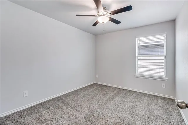 an empty room with a ceiling fan and a window