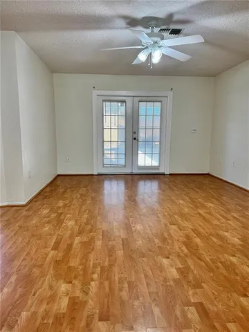 a view of an empty room with window and chandelier fan