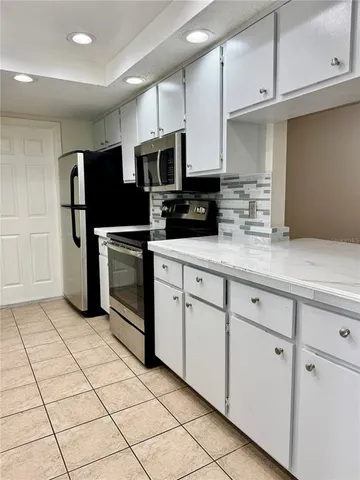 a kitchen with stainless steel appliances kitchen island granite countertop a refrigerator sink and microwave