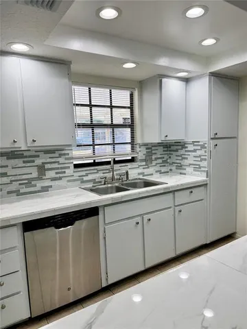 a kitchen with granite countertop a sink and white cabinets
