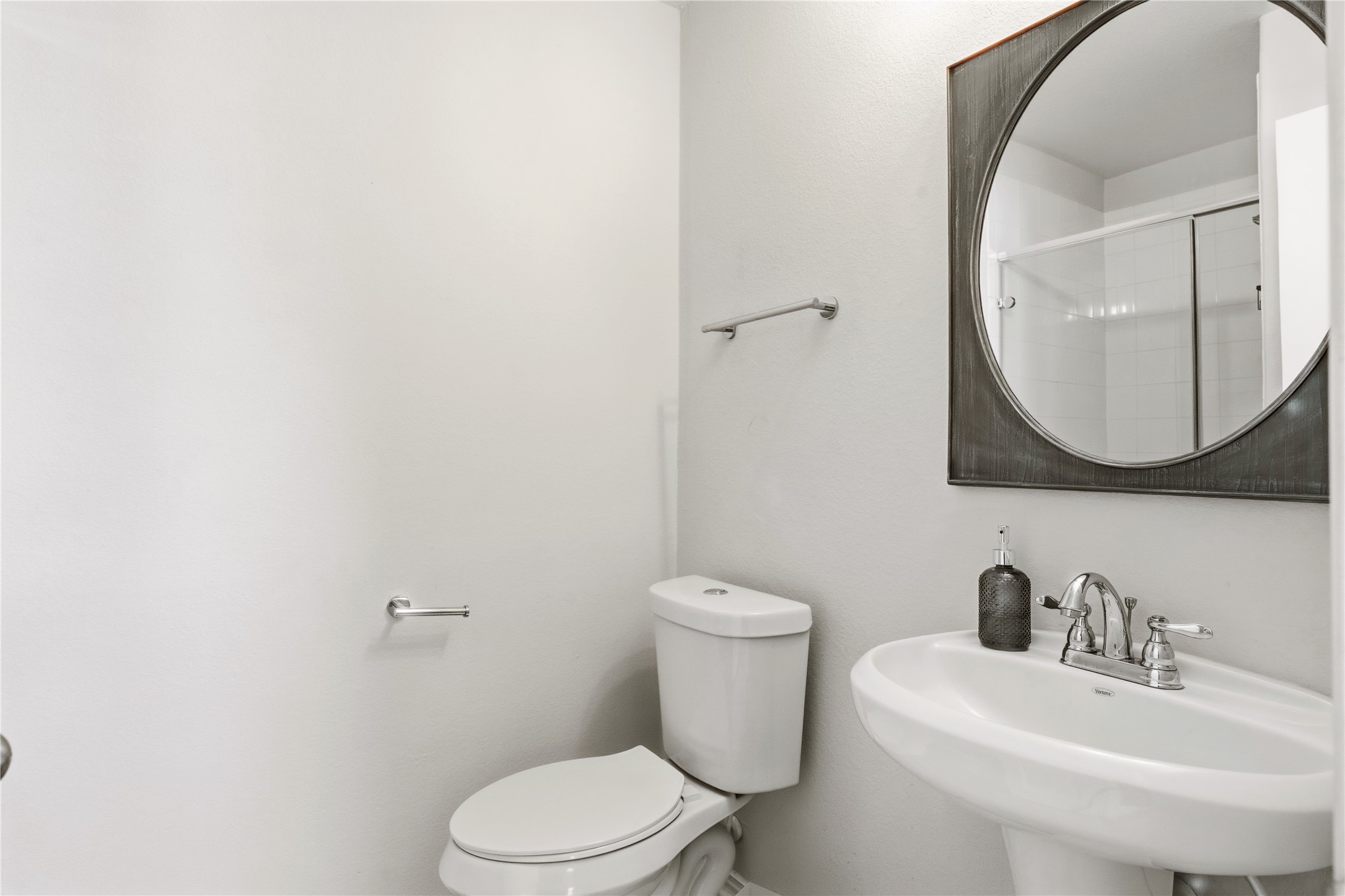 486 Pond View Pass Buda, TX 78610 - Photo 22 of 39 Bathroom featuring a pedestal sink, white toilet, and a circular mirror with a dark frame