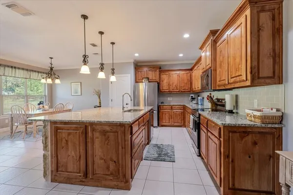 a kitchen with stainless steel appliances granite countertop a sink a stove and a wooden floors