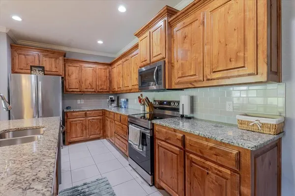 a kitchen with stainless steel appliances granite countertop a stove a sink dishwasher and a refrigerator with wooden cabinets