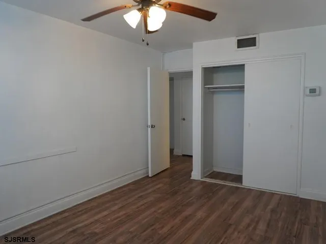 an empty room with wooden floor and fan