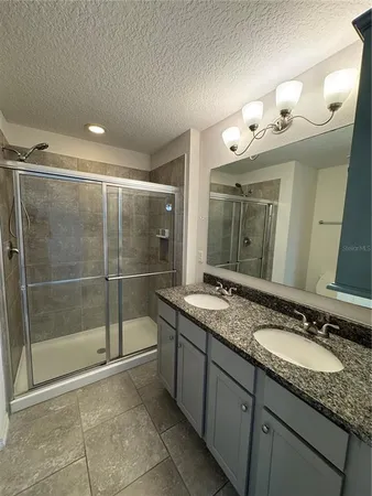 a bathroom with a granite countertop sink a mirror and a shower