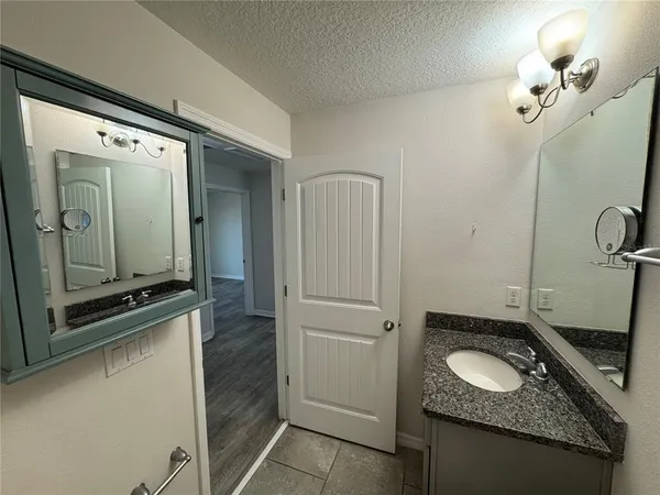 a bathroom with a granite countertop sink a mirror and a shower