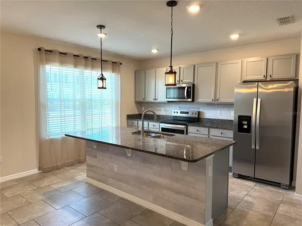 a kitchen with stainless steel appliances granite countertop a refrigerator a sink a stove and island