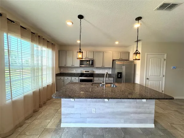 a kitchen with kitchen island a large counter top appliances and cabinets