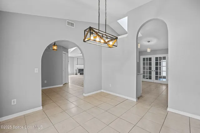 an empty room with windows fireplace and a kitchen view
