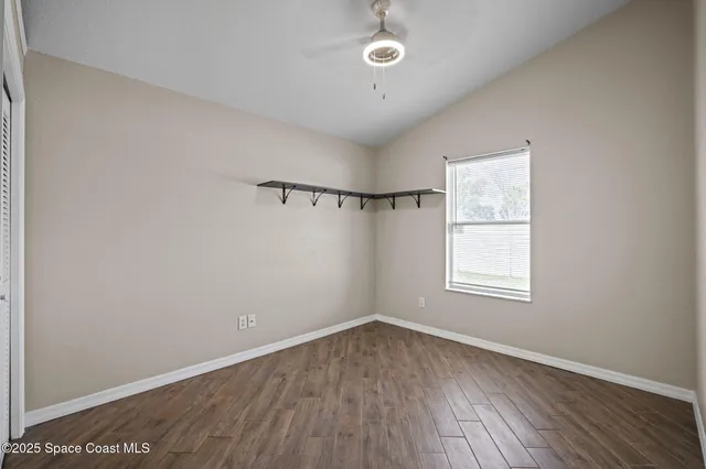 an empty room with wooden floor closet and windows