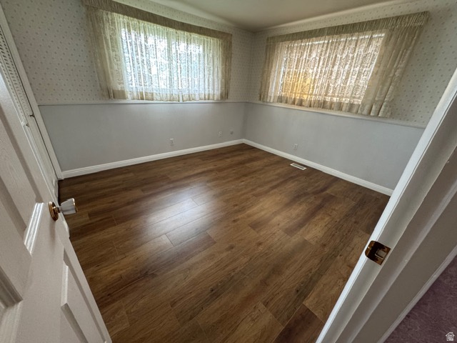 588 North 4500 West West Point, UT 84015 - Photo 22 of 61 Unfurnished bedroom featuring dark wood-style laminate flooring, wallpapered walls, and a closet