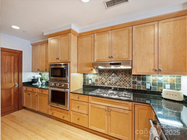 a kitchen with stainless steel appliances granite countertop a stove a sink and a microwave