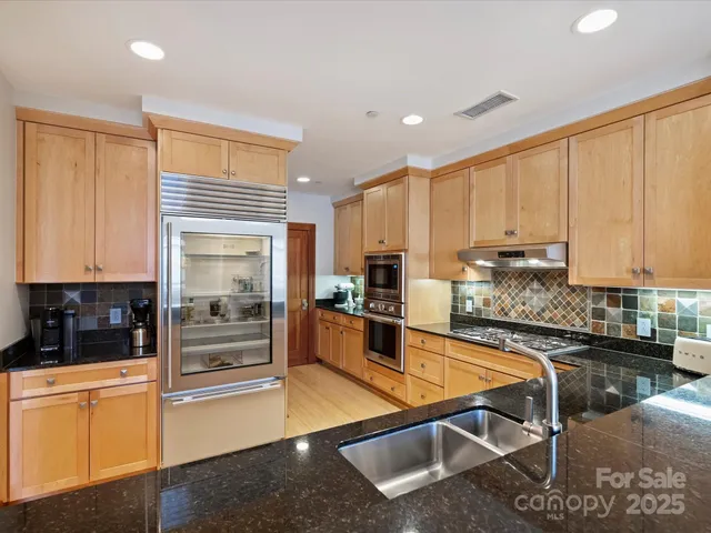 a kitchen with stainless steel appliances granite countertop a refrigerator a stove and white cabinets with wooden floor