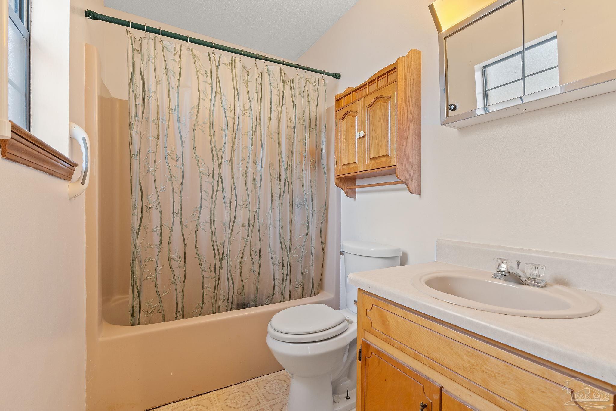 2329 Camors Road Jay, FL 32565 - Photo 21 of 28 a bathroom with a sink a toilet and shower curtain