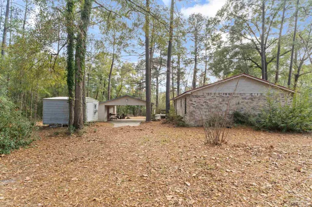 a backyard of a house with a large tree and wooden fence
