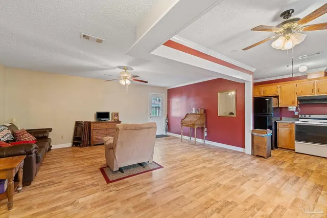 a living room with furniture a flat screen tv and kitchen view